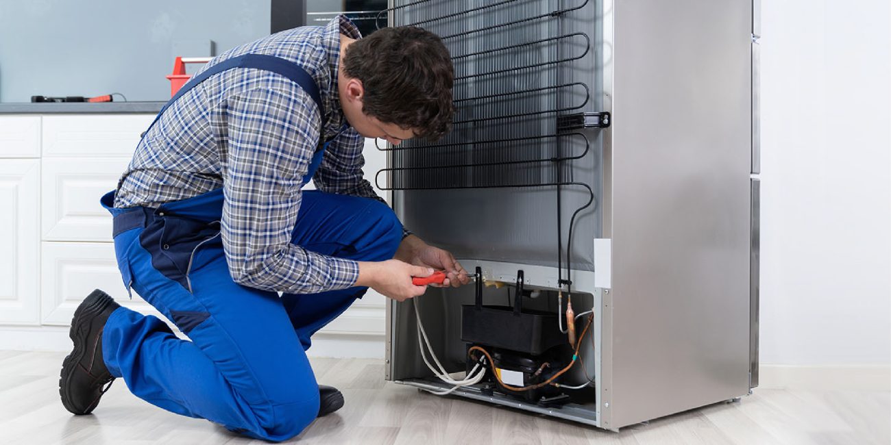 Technician inspecting a refrigerator in a kitchen.
